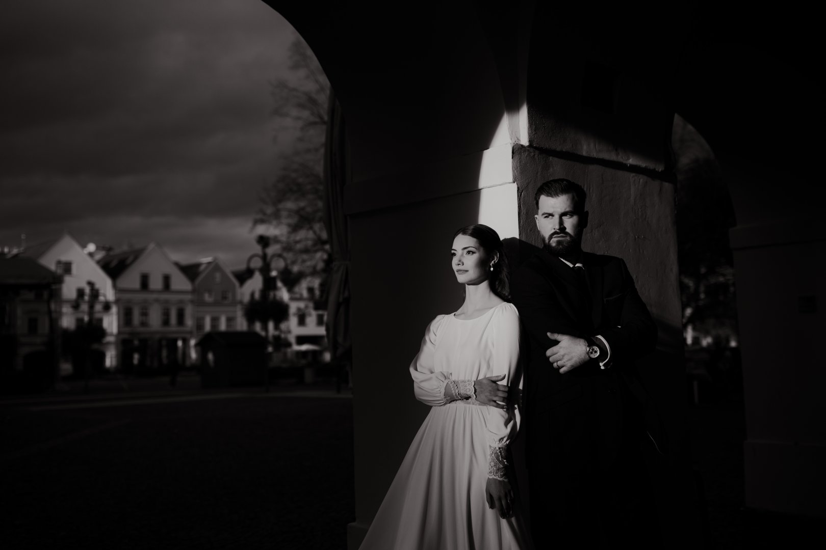 Umelecký čiernobiely svadobný portrét nevesty a ženícha v historickom podloubí od fotografa Adriána Juríčka.
