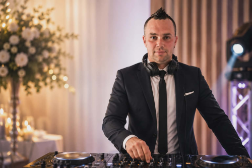 Profesionálny Deejay pro Váš event v elegantnom obleku so slúchadlami za mixážnym pultom na svadbe.