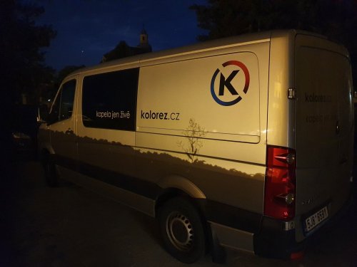 Dodávka hudobnej skupiny KOLOREZ band s logom a nápisom kapela jen živě zaparkovaná v noci.