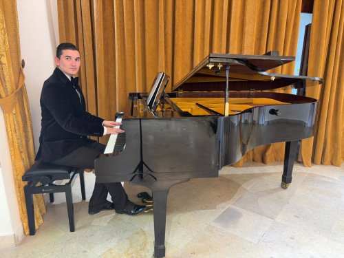 Patrik Bohunský z Golden Keys v elegantnom obleku hrá na čiernom krídle pred zlatým závesom.