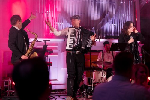 Hudobná skupina KOLOREZ band naživo na pódiu s akordeónom, saxofónom a speváčkou počas vystúpenia na svadbe.