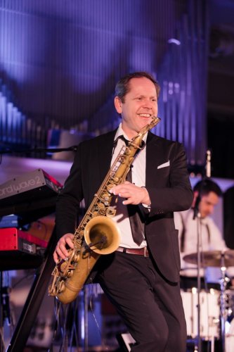 Usmievavý saxofonista z hudobnej skupiny KOLOREZ band počas energického vystúpenia na svadbe.