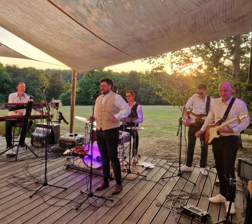 Hudobná skupina KOLOREZ band vystupuje na vonkajšom pódiu počas svadobnej oslavy pri západe slnka.