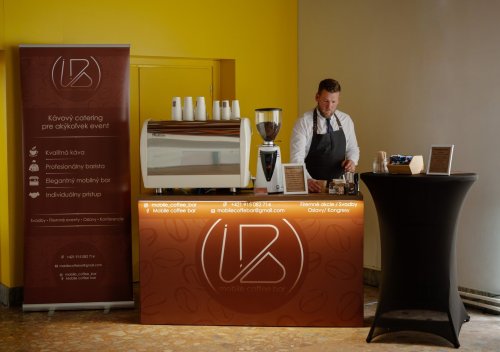 Profesionálny barista pripravuje kávu v elegantnom Mobile Coffee Bar na svadobnej hostine.