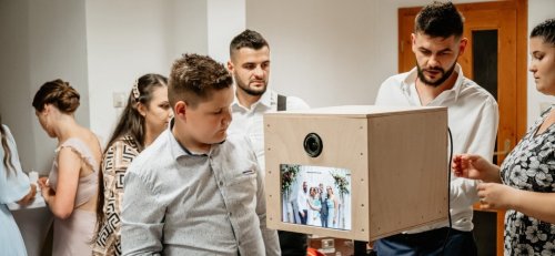 Hostia na svadbe sledujú náhľad svojich fotografií na displeji modernej drevenej svadobnej fotobúdky od fotobudken.sk.