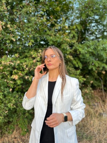Svadobná koordinátorka Saskia z Wedding Fairy počas telefonickej konzultácie v bielom saku v exteriéri.
