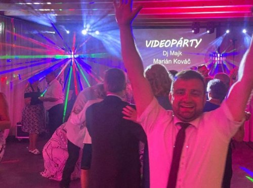 Hostia sa zabávajú na tanečnom parkete počas videopárty, ktorú moderuje a hudobne doprevádza Dj a moderátor pod farebnými svetelnými efektmi.