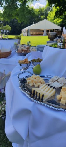 Elegantný syrový podnos na vonkajšej svadobnej hostine od Empresa catering & events s rôznymi druhmi syrov, olivami a krekrami.