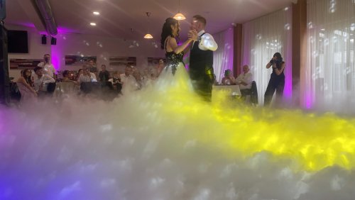 Novomanželský tanec v oblakoch dymu s osvetlením od DJ-a a moderátora na svadobnej hostine