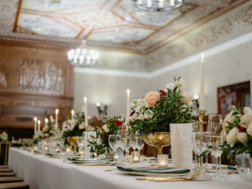 Elegantne prestretý svadobný stôl s kvetinovou výzdobou a sviečkami v historickej sále Hotela Grand Vígľaš.