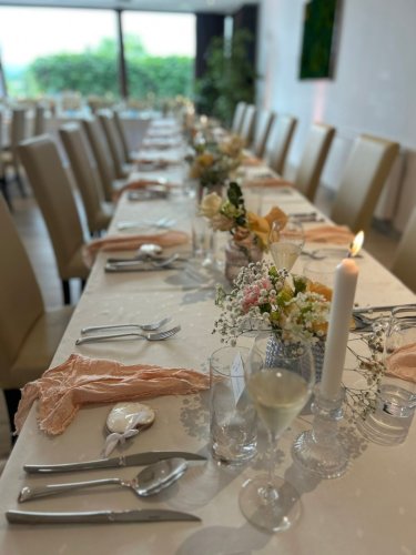 Elegantne prestretý dlhý svadobný stôl v hoteli Belassi s kvetinovou výzdobou a sviečkami.